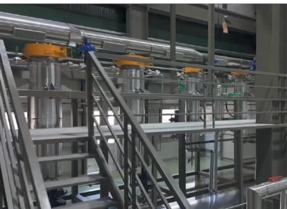 Extraction bay with stainless steel extractor and separator columns behind a handrail.
