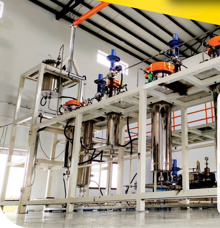 Multi-vessel supercritical CO2 extraction skid installed inside a factory shed, with extractor and separator columns under a crane beam.