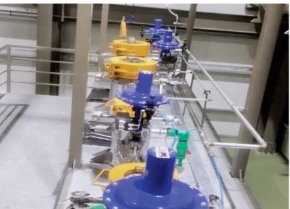Close view of a high-pressure valve manifold with blue and yellow actuators along the extraction line.